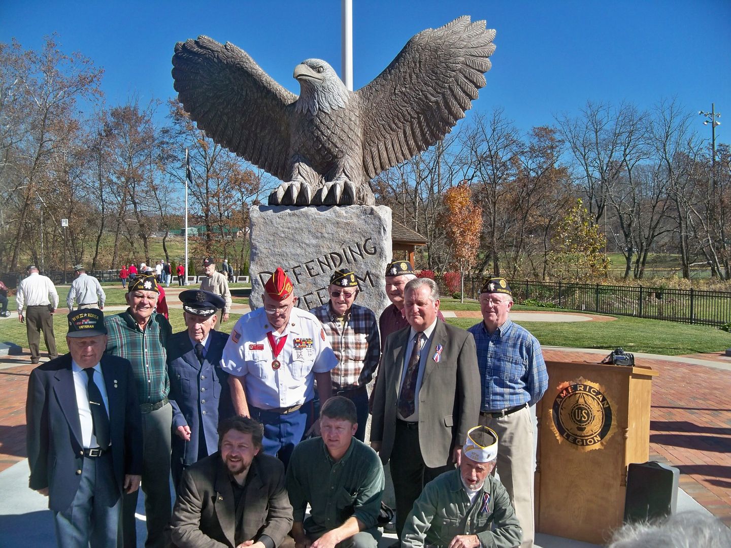 Alexei Kazantsev (leftmost on 1st row) poses with his sculpture and the Veterans Memorial Committee at the Macon County Veterans Memorial Park on November 11, 2010 
Photo by Bobby Coggins