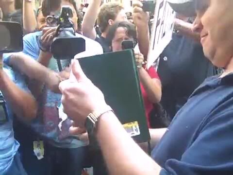 Screencap from a video showing an anonymous American exercising his Freedom of Speech 
Note the mob of reporters who are just shocked that such a man exists in this land of ours 
Screencap by Bobby Coggins